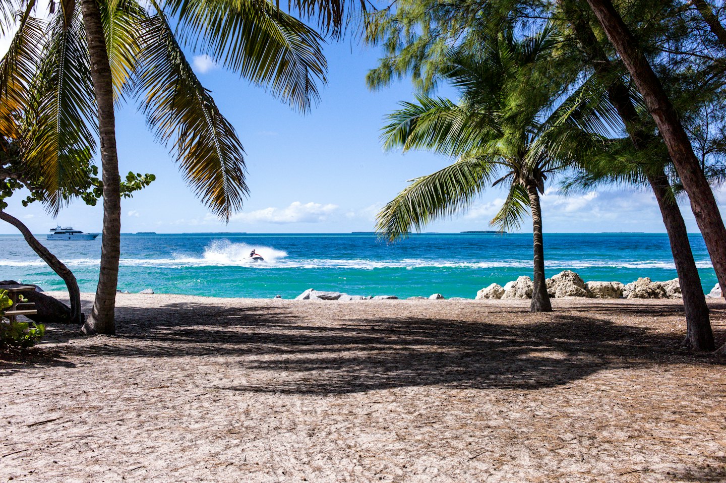 A person rides a jet ski across the tropical ocean.