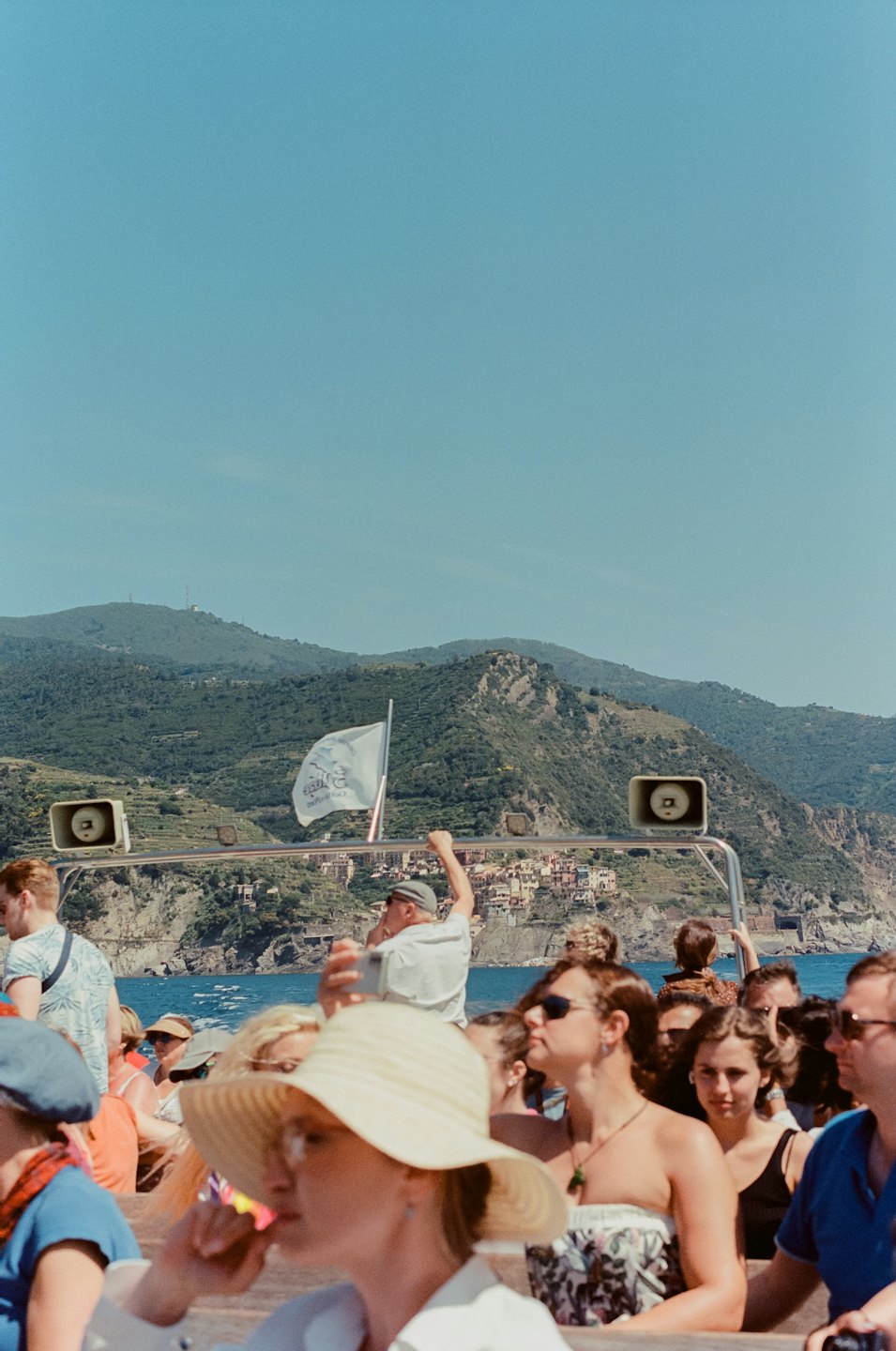 Tourists on a boat looking toward a coastal village.