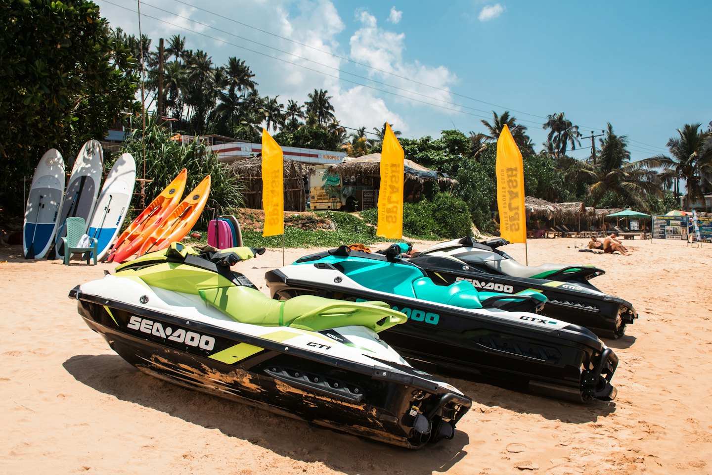 Three jet skis parked on the beach with rental equipment.