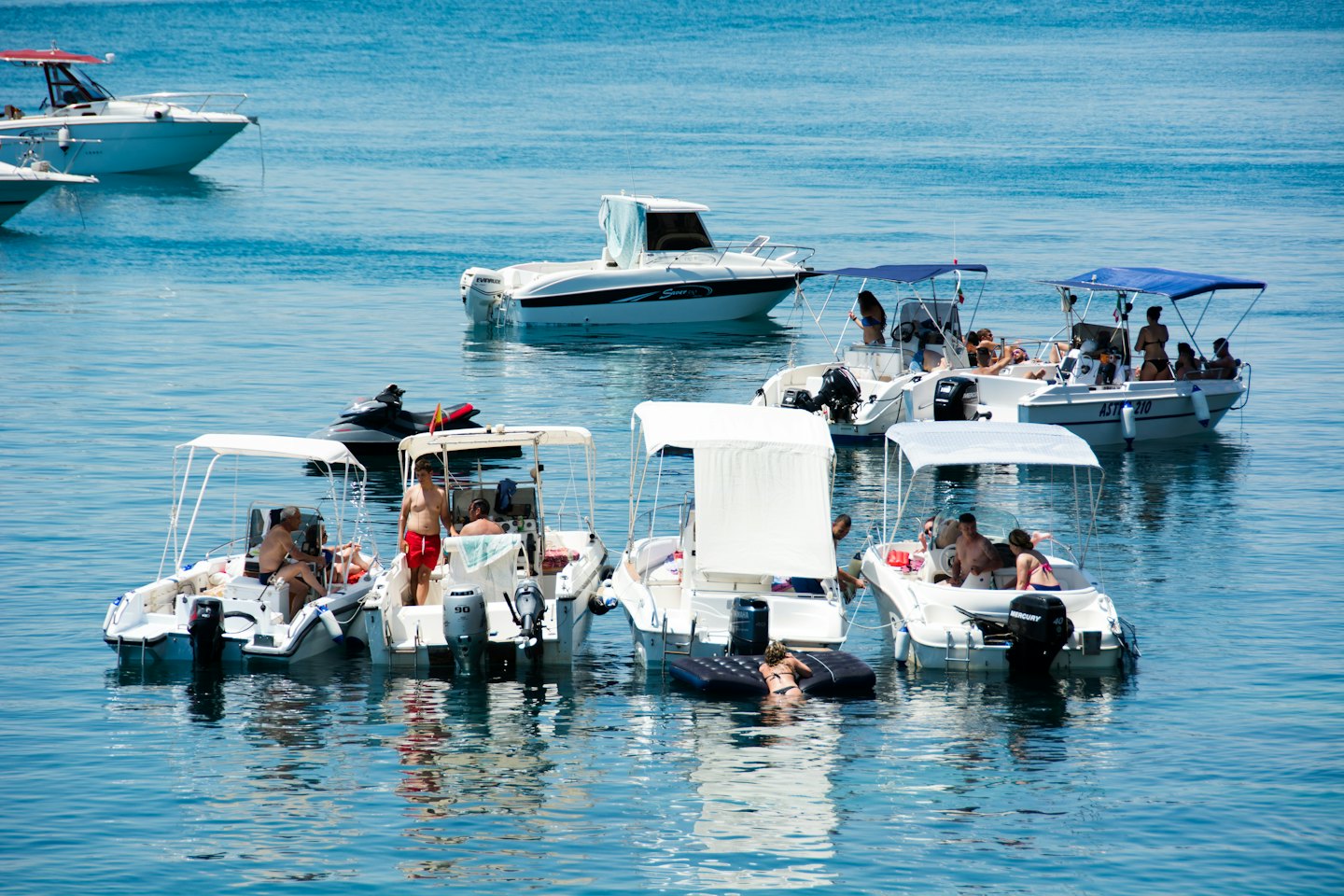 People enjoy leisure boats and jet skis in clear water.