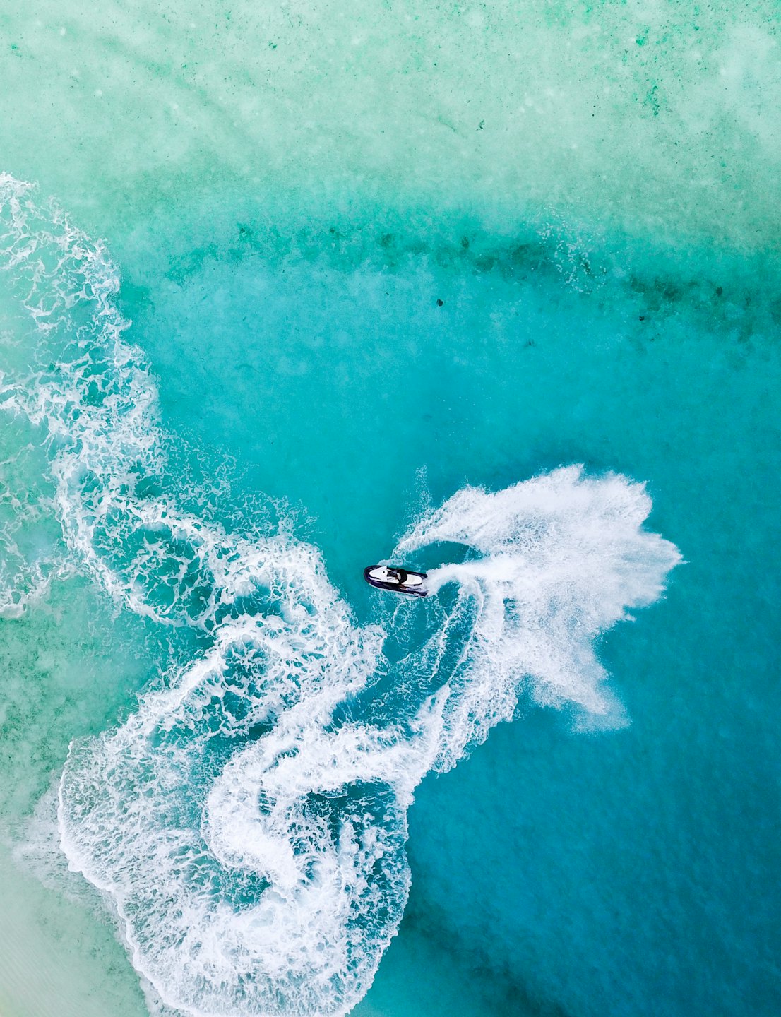 Person riding a jet ski in clear turquoise water.