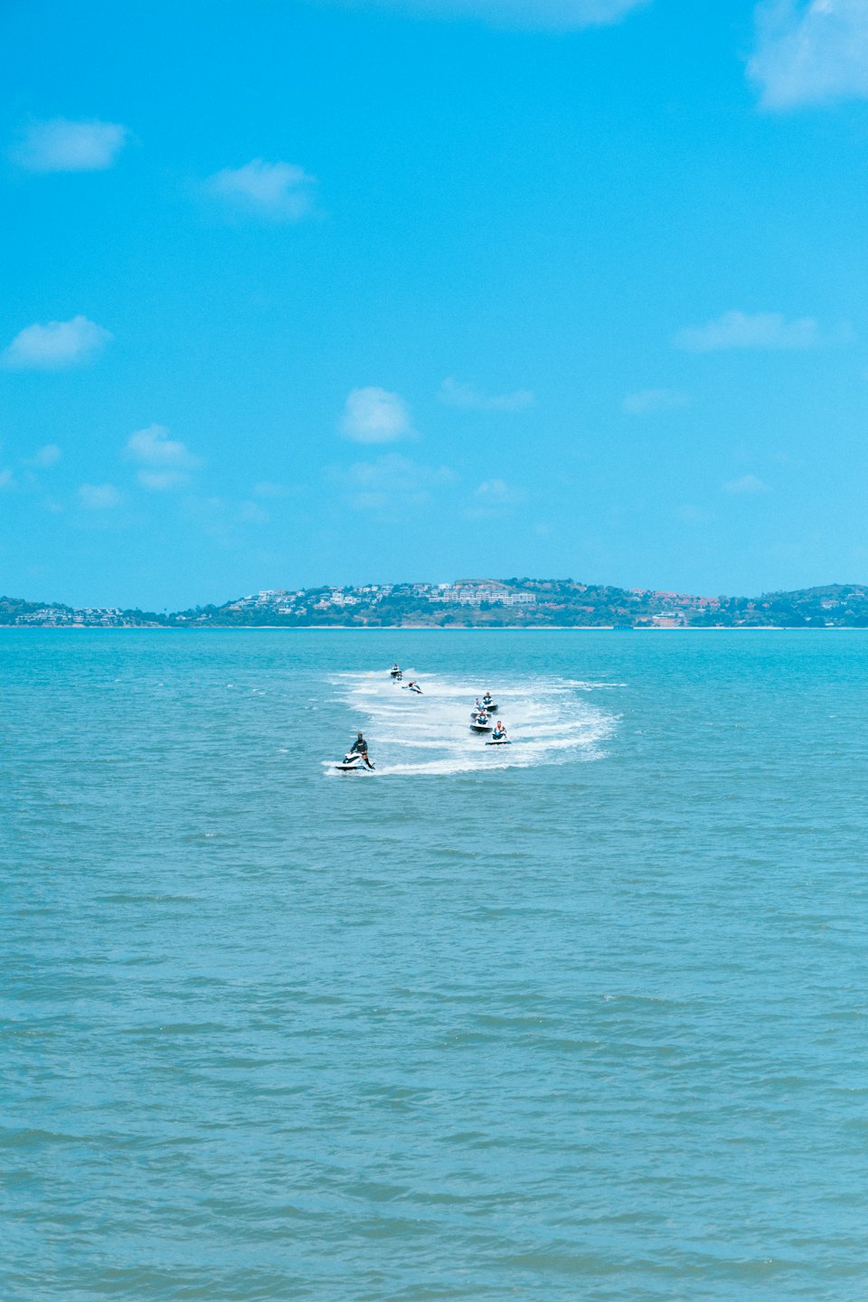 People riding jet skis across the blue ocean water.